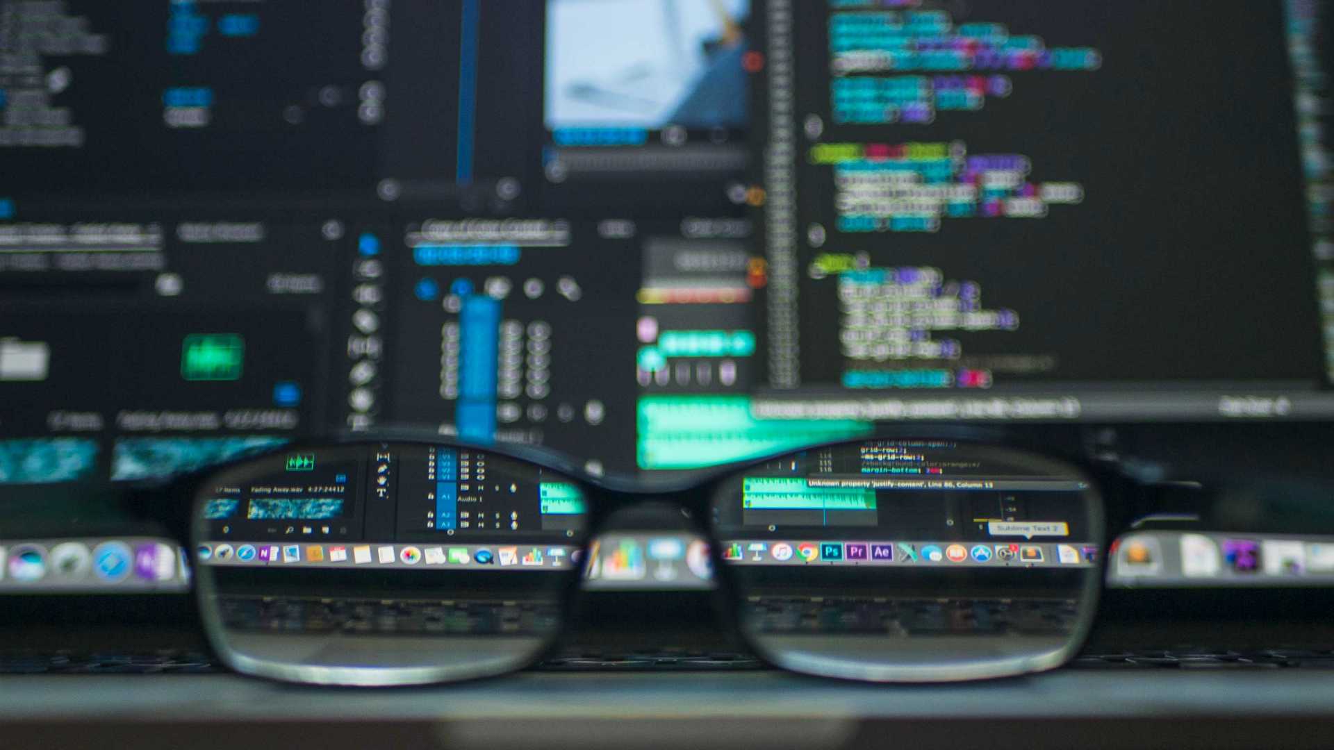 glasses in front of computer screens with code