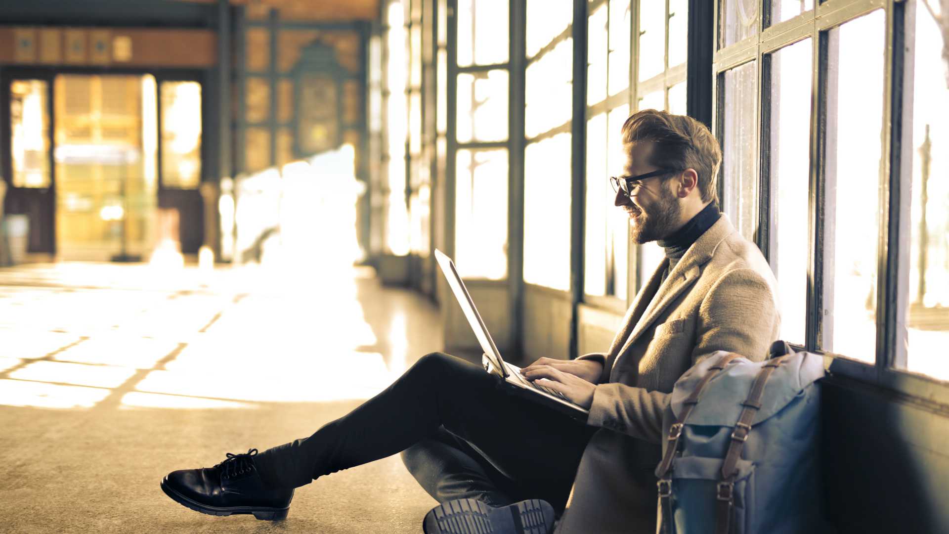man in blazer working on a laptop in a hallway