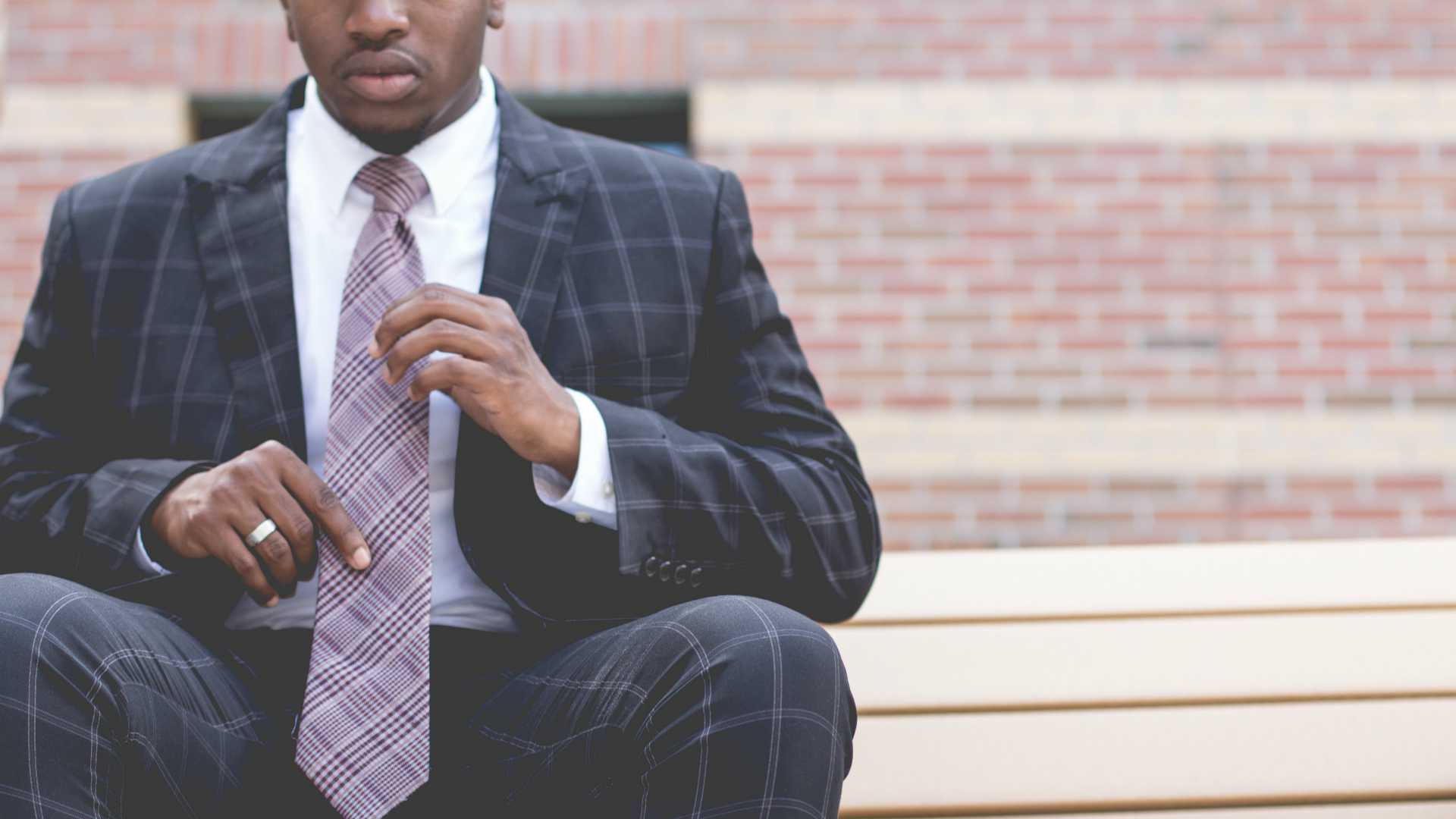 man wearing a tie in front of a brick building