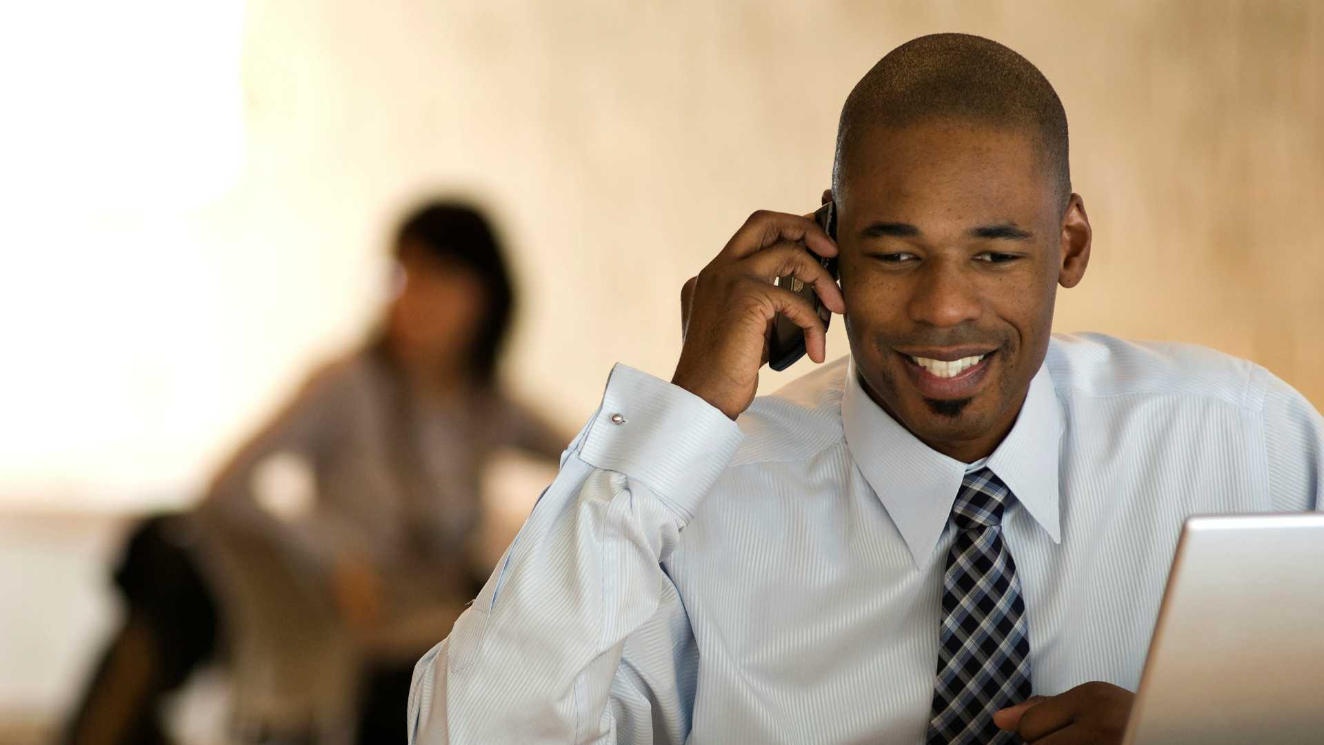 man talking on a phone and using a laptop