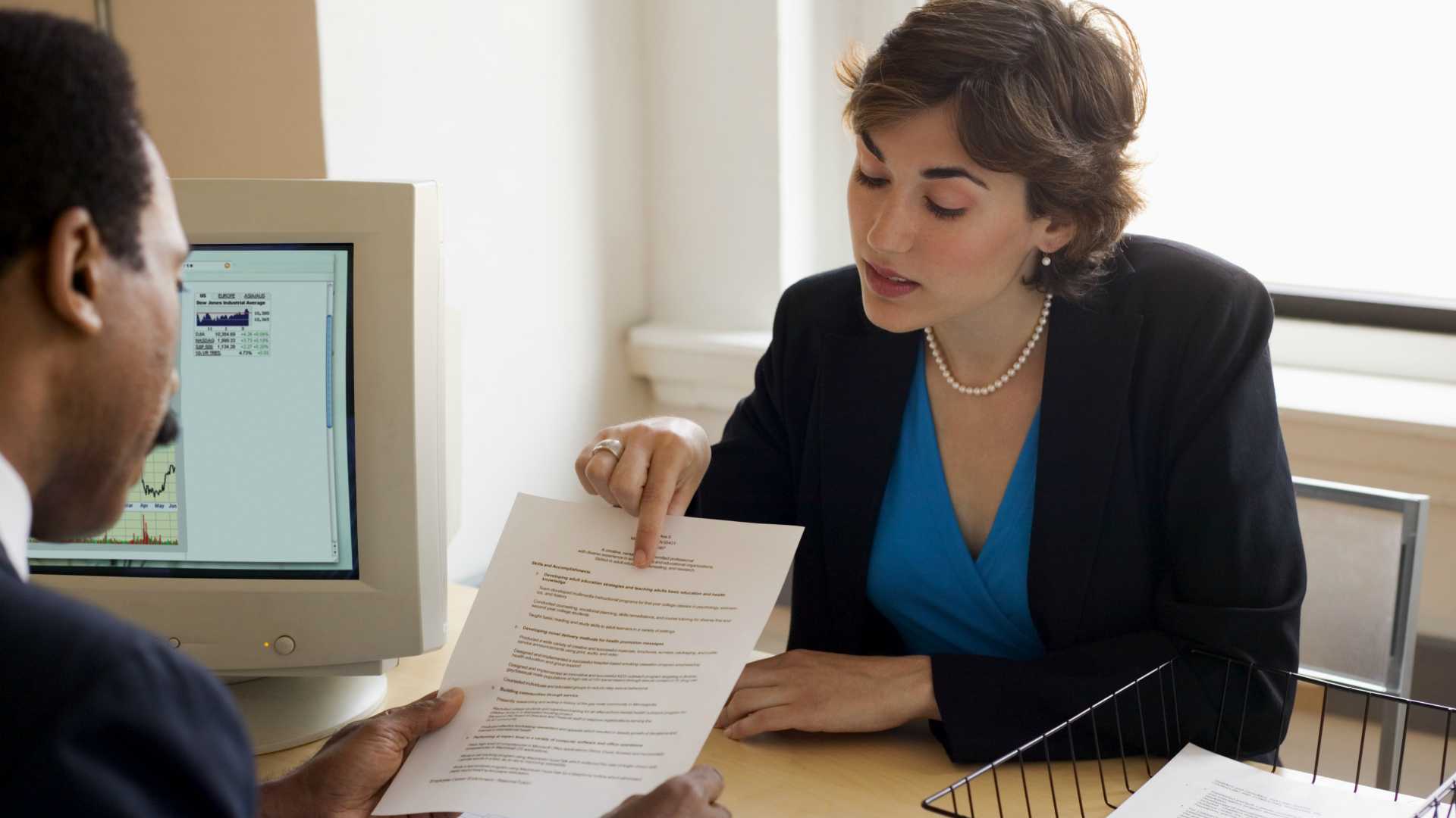 businseswoman pointing at a document that a businessman is holding