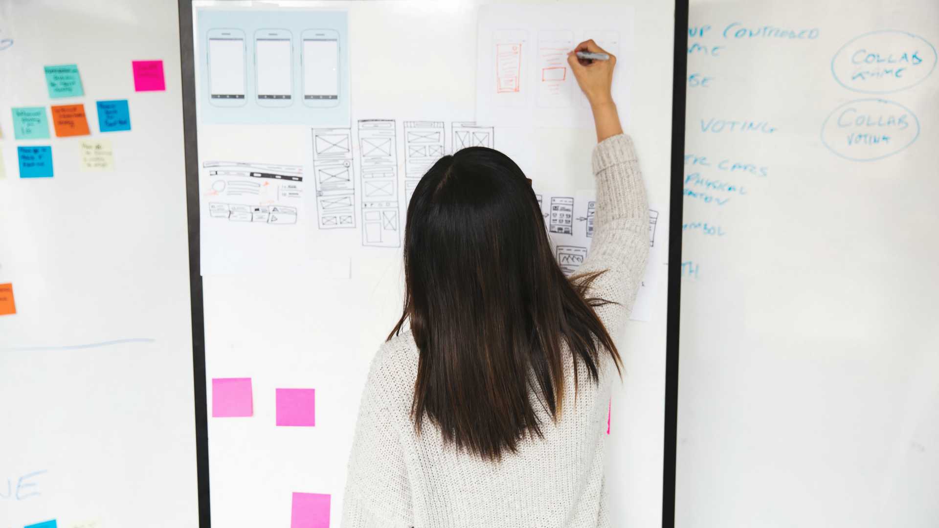 woman outlining a design on a whiteboard