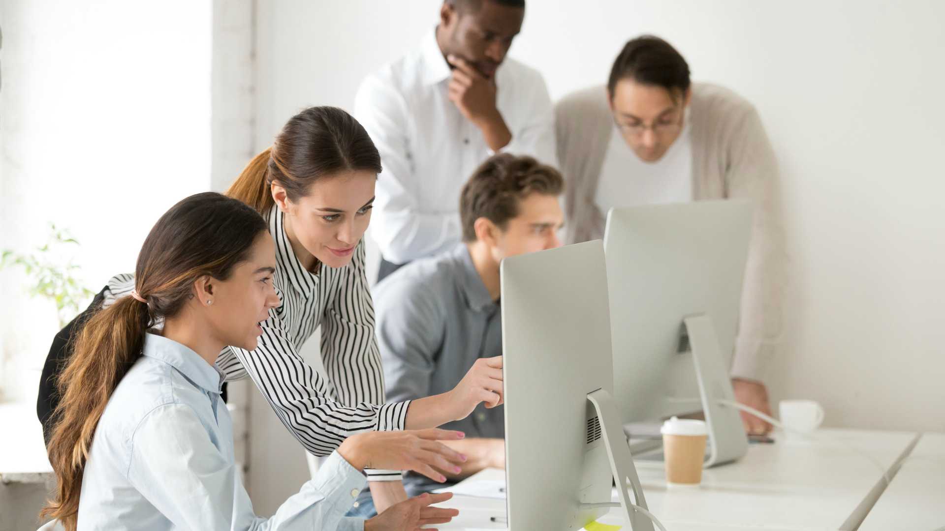 professional woman explaining a tech concept to another woman, pointing at the computer