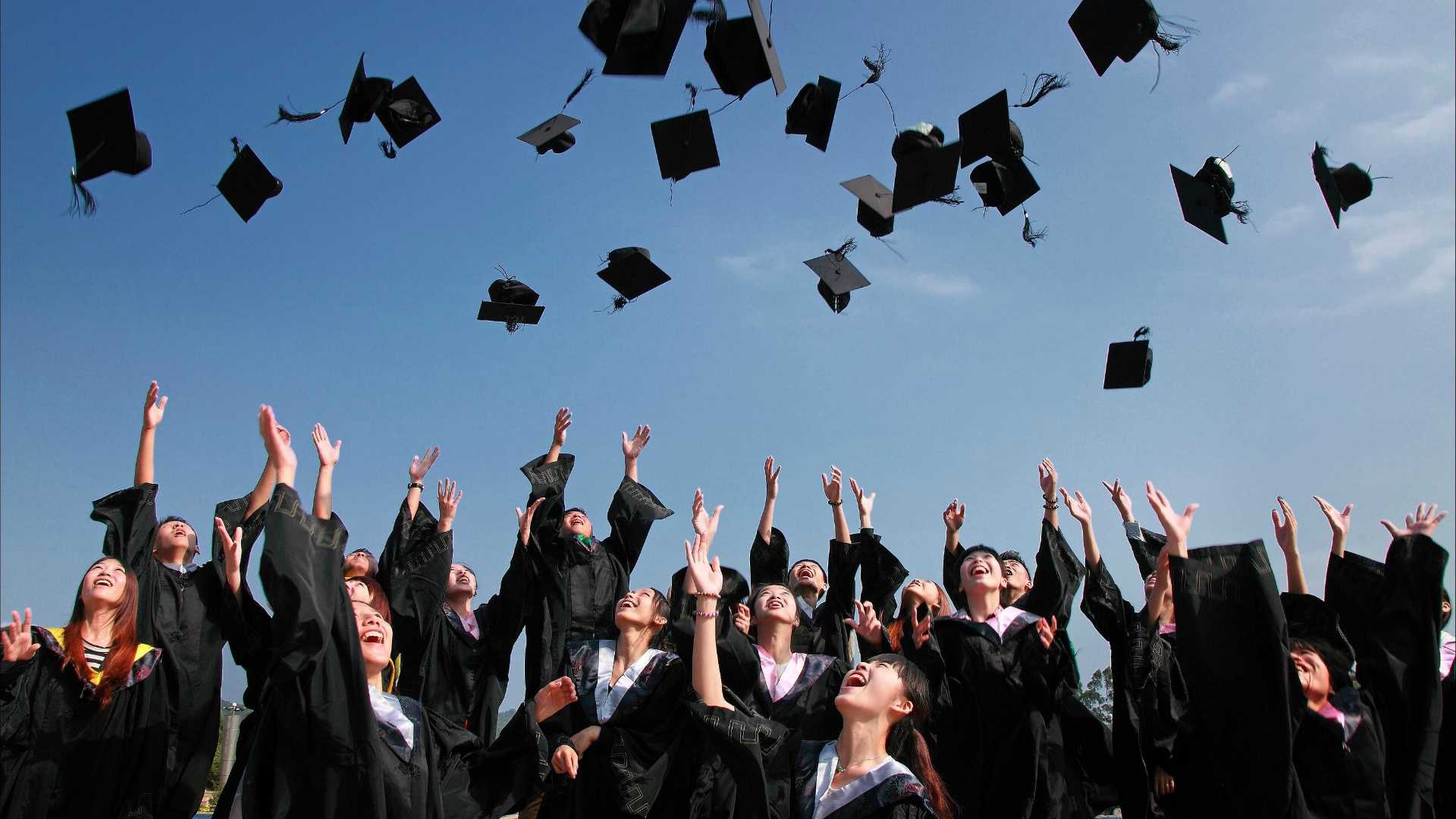 graduating class of women throwing their caps in the air
