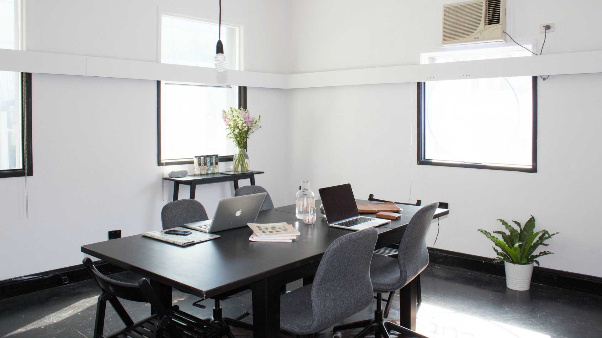 well-lit meeting room with no people but a couple of laptops and other materials on the table