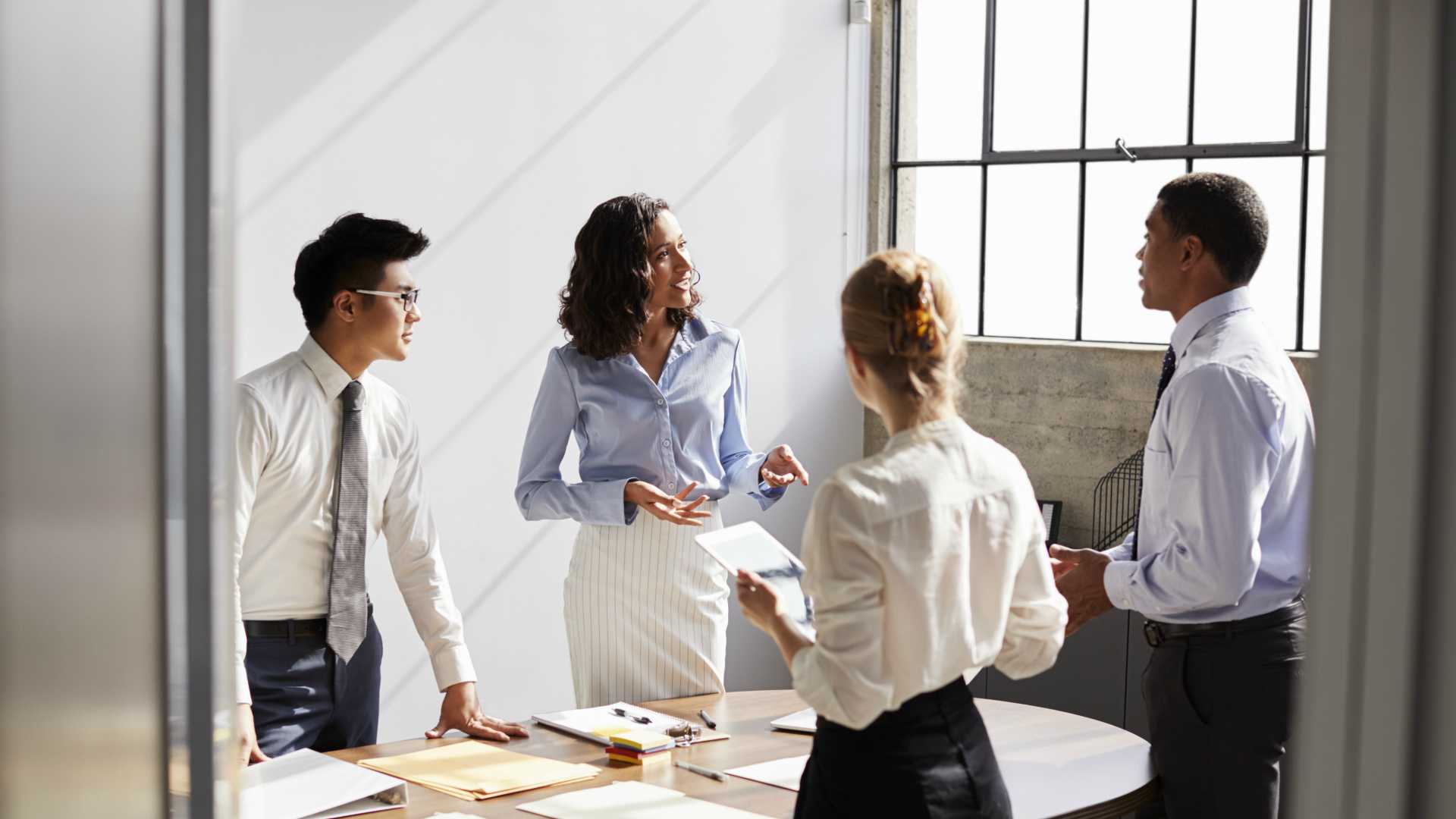 two businessmen and two businesswomen standing around a table having a discussion