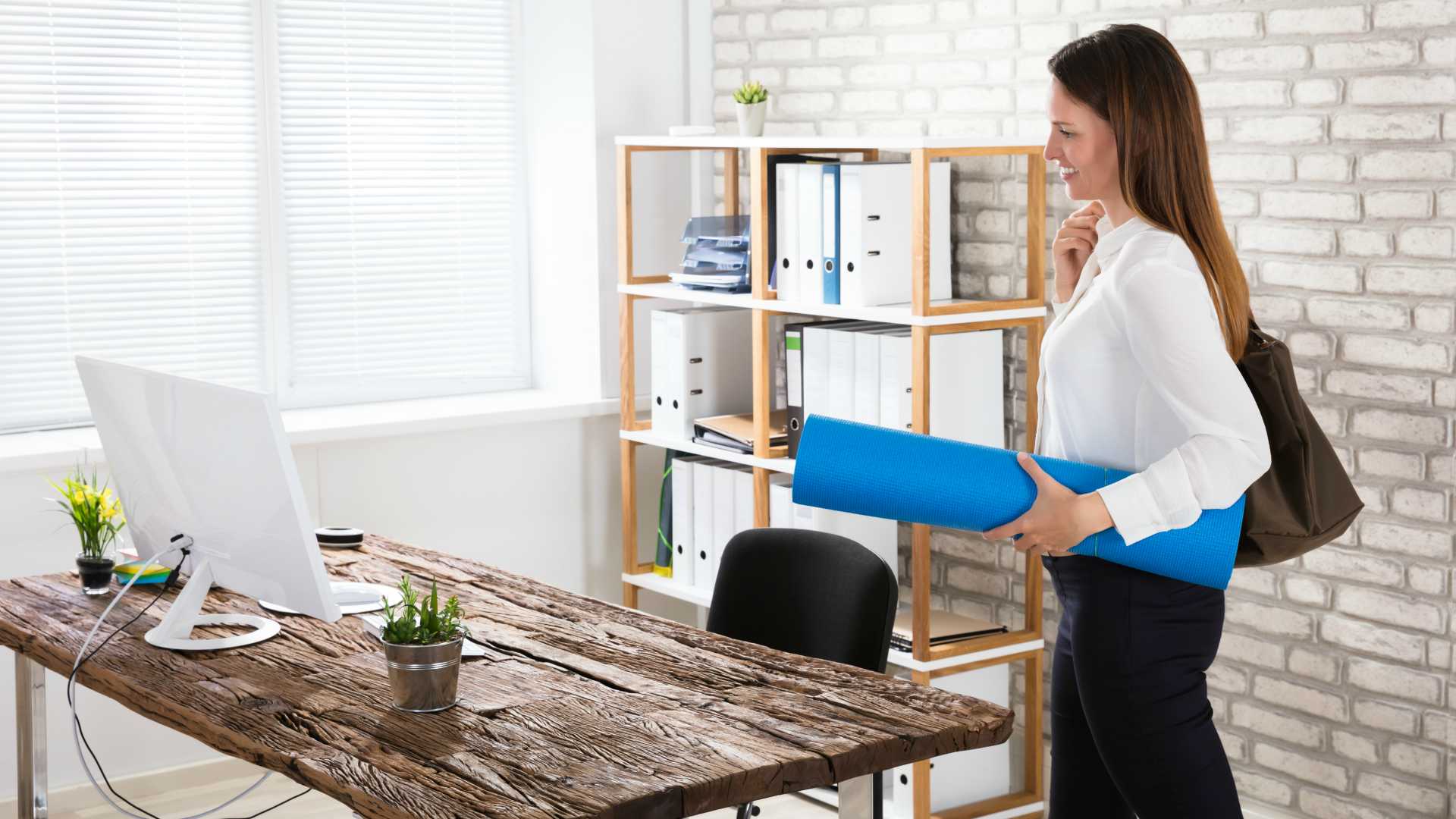 businesswoman walking into her office, carrying a yoga mat