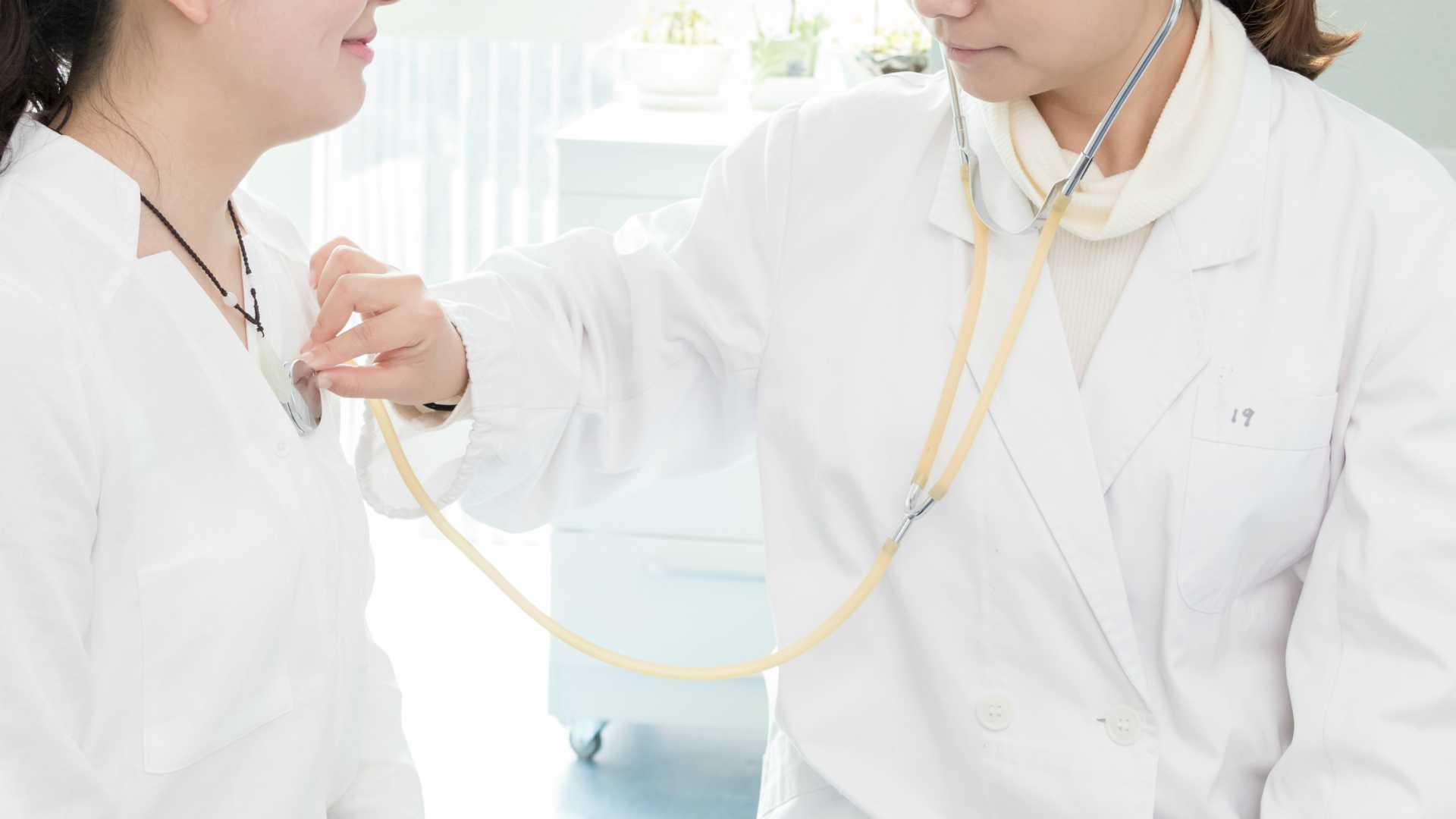 Female doctor checking heartbeat of female patient with stethoscope