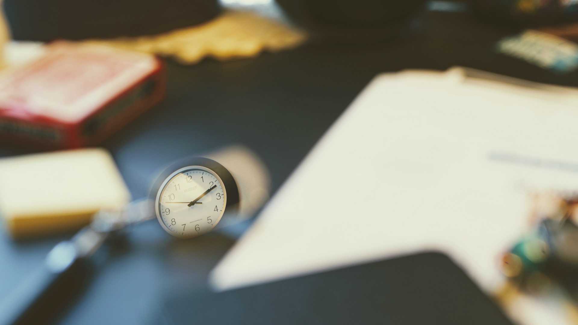 watch sitting on a desk with notebooks on it