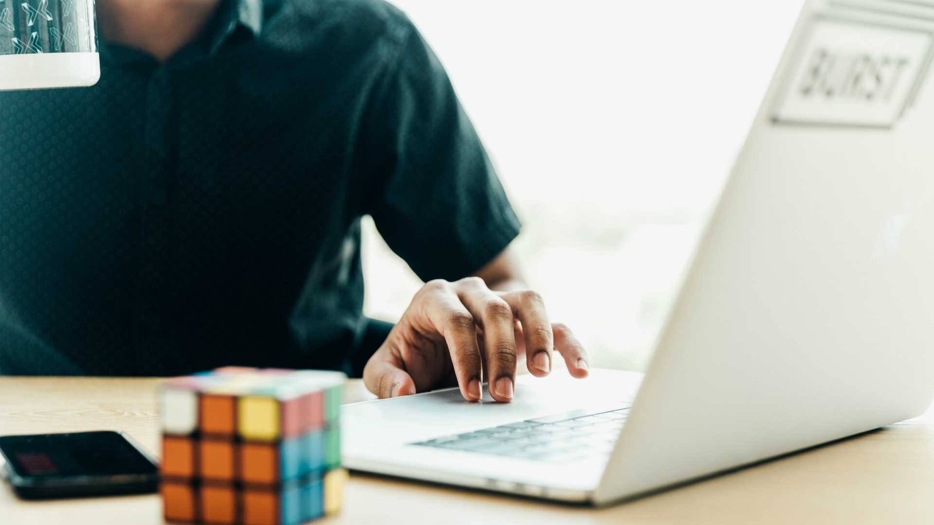 Businessperson sitting at desk with laptop and rubix cube