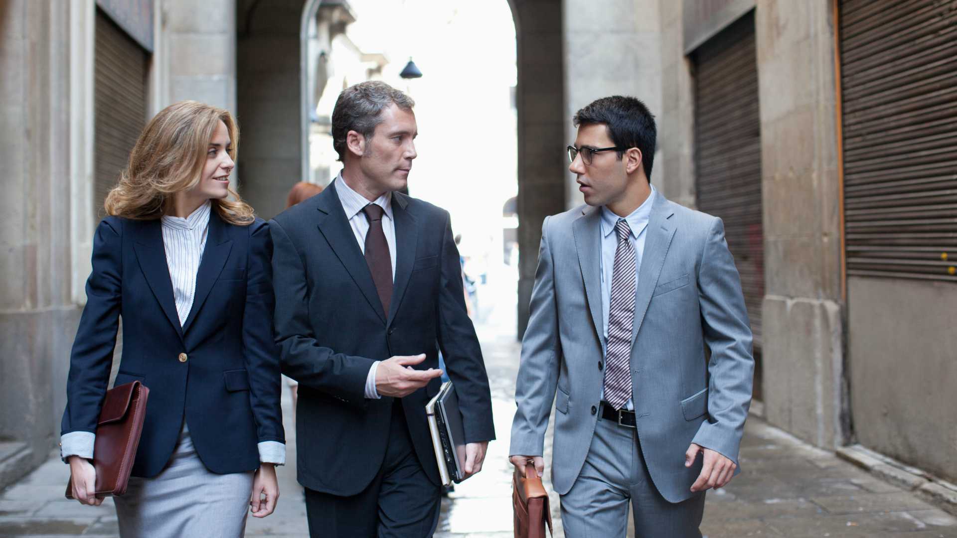 Businessmen and businesswoman walking down the street, discussing leadership