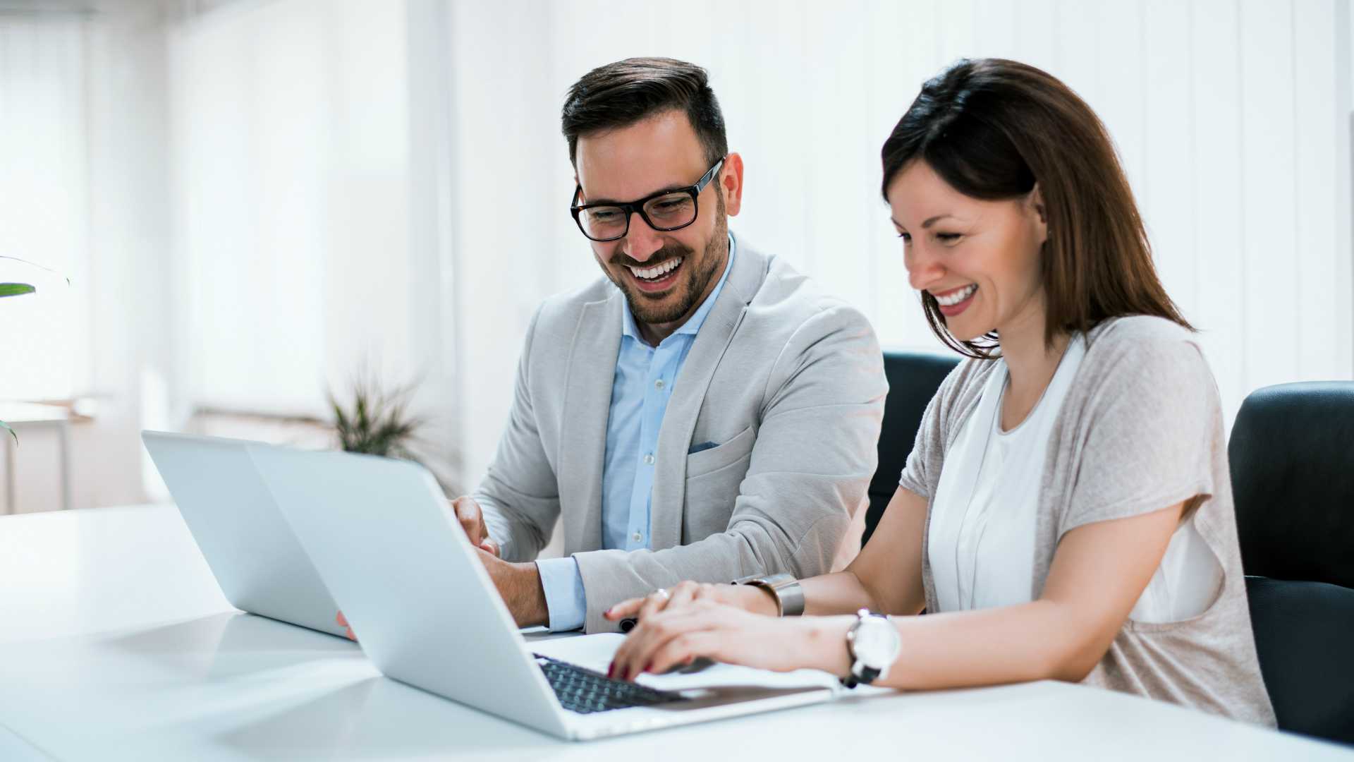 Businesspeople working together in bright office, sitting at desk.