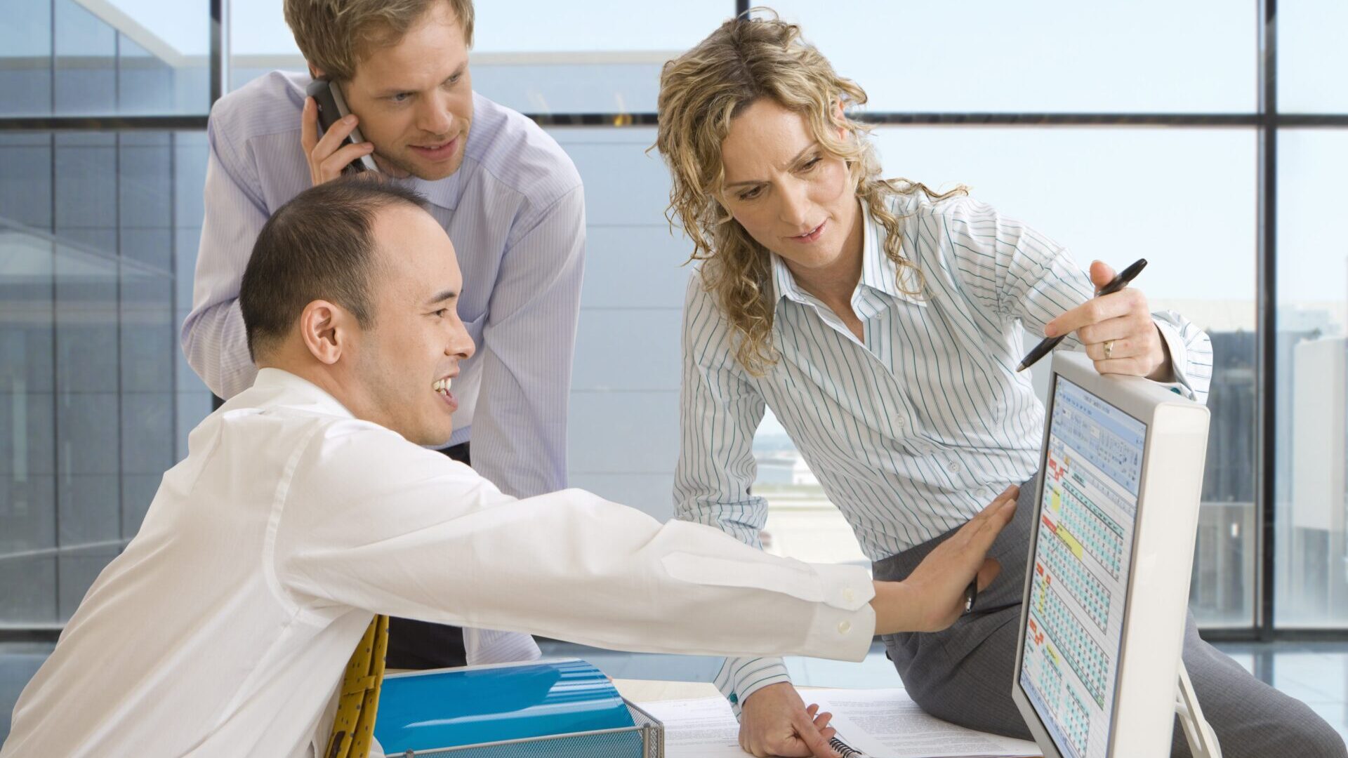 Businessmen and businesswoman at desk working at computer in office