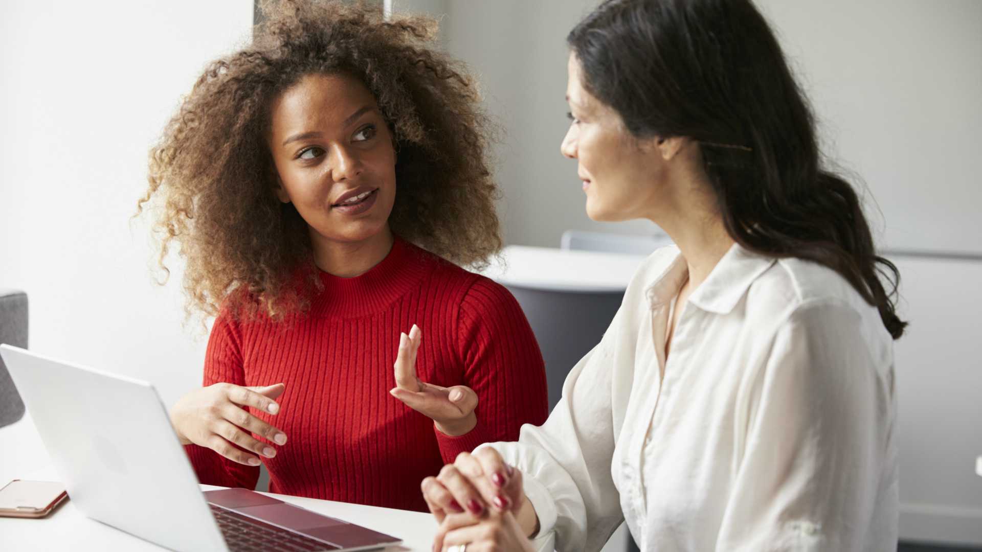 Young female business maanger providing performance review to female employee