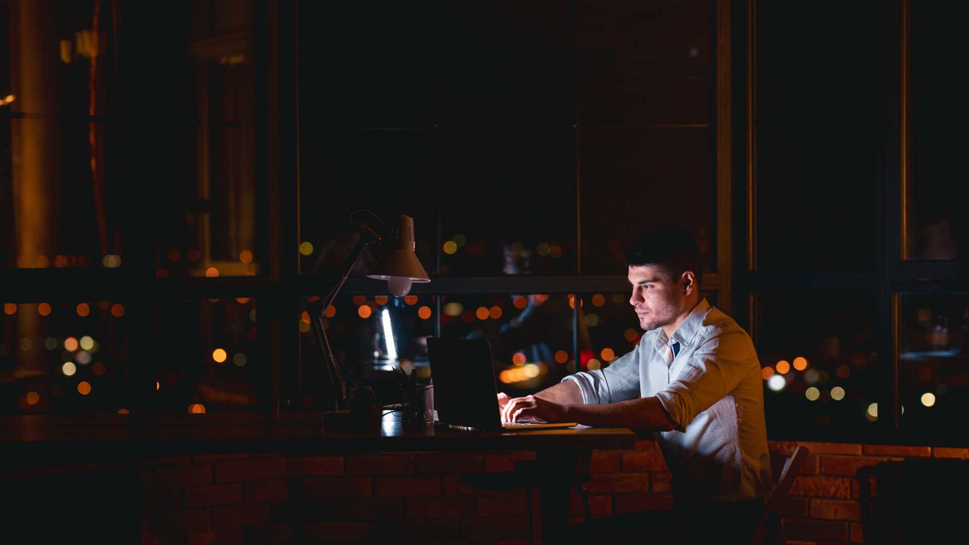 Young businessman working late into the evening in urban apartment