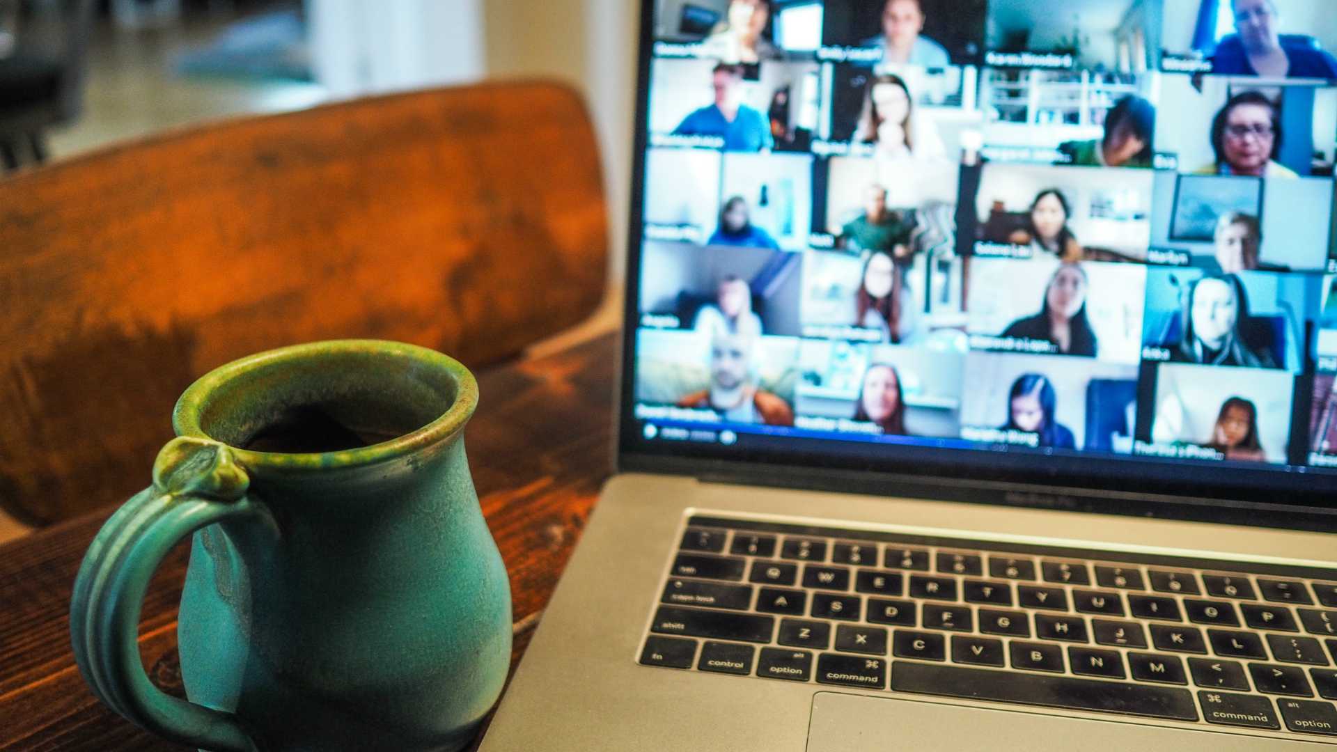 Laptop open with video call open with coffee mug sitting in front of laptop