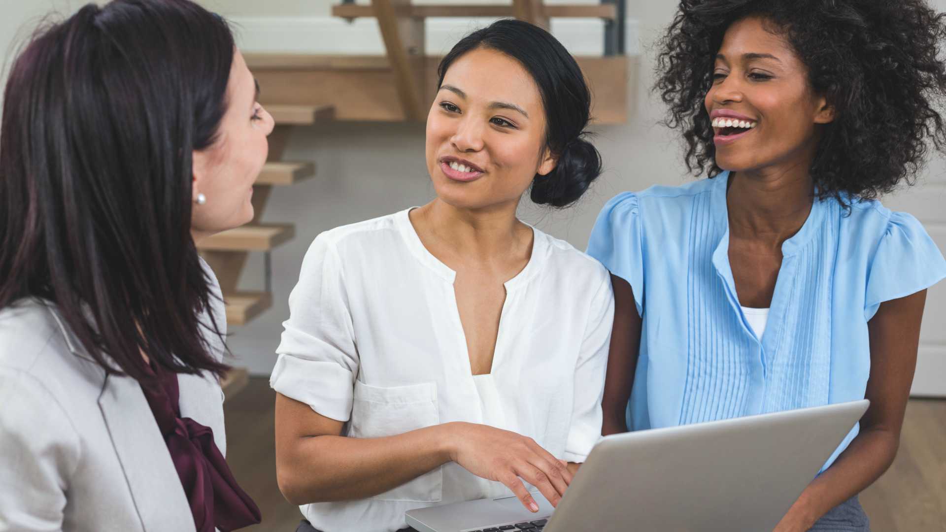 Three racially diverse female colleagues talking about their leadership development programs together