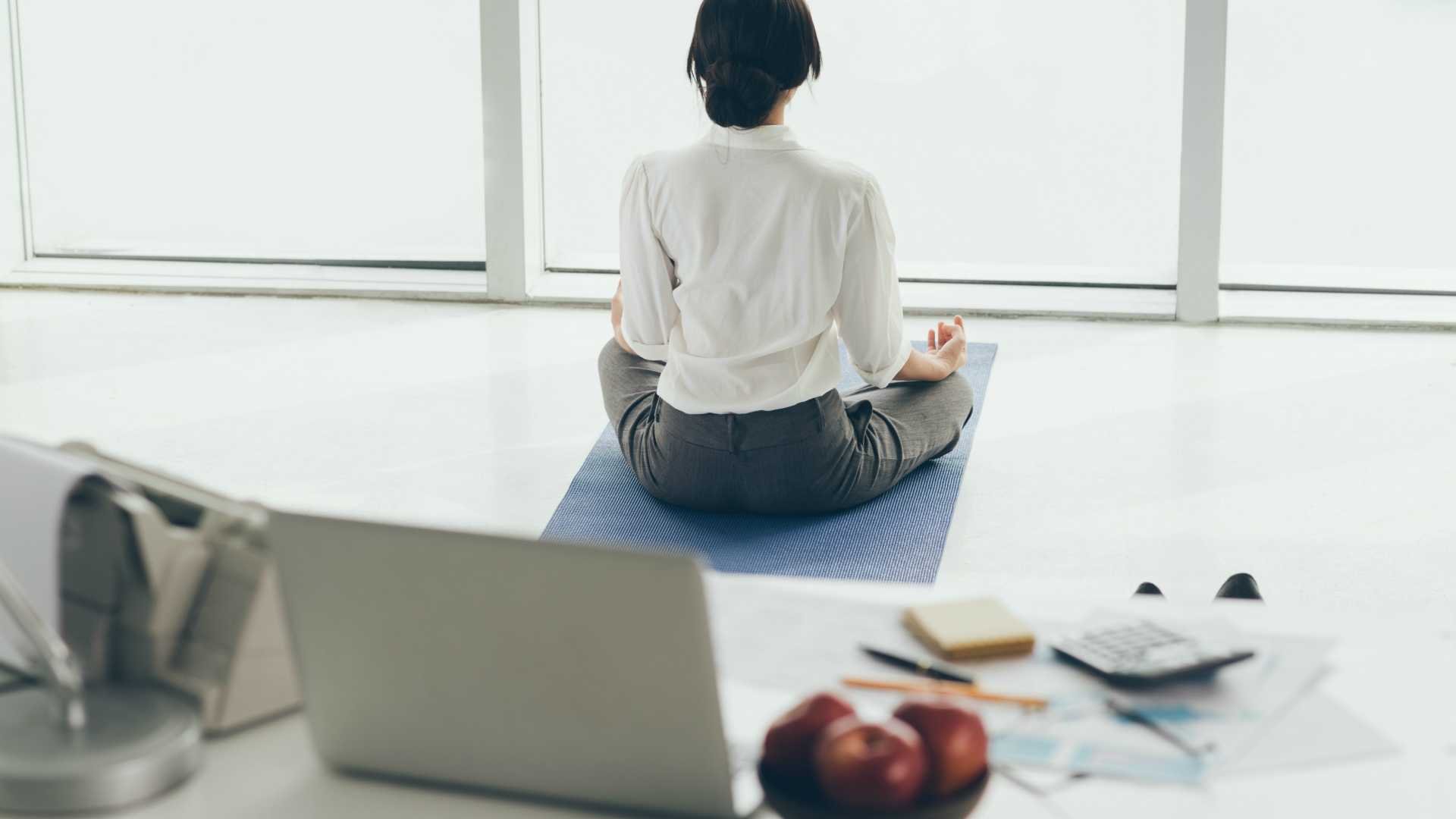 Office worker meditating on the floor, rear view