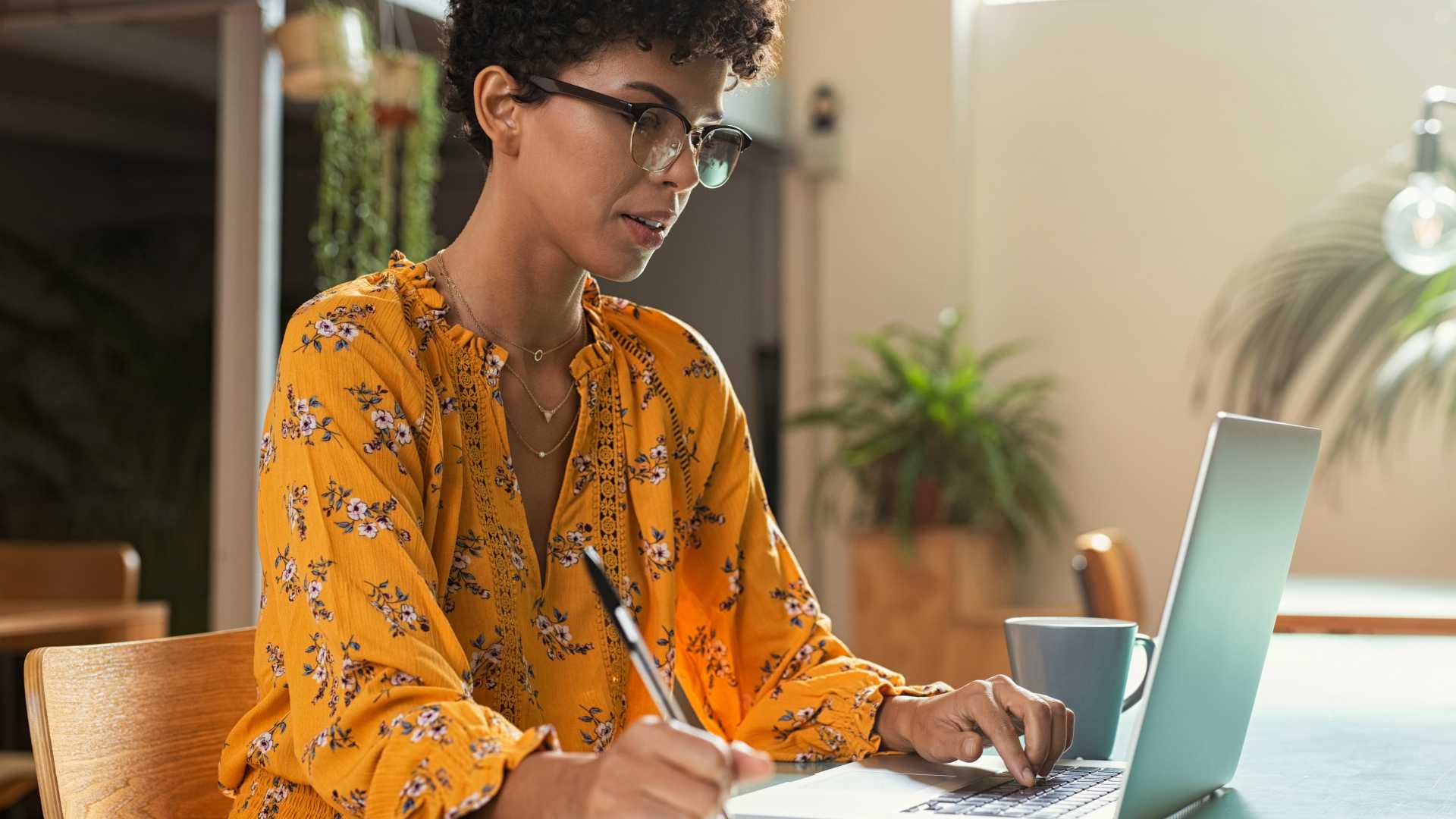woman working on a laptop and taking notes