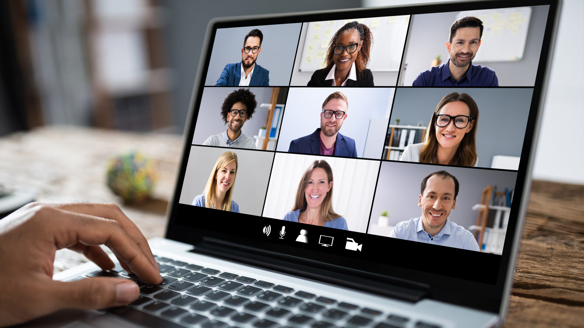 A laptop screen showing an online video meeting with nine attendees
