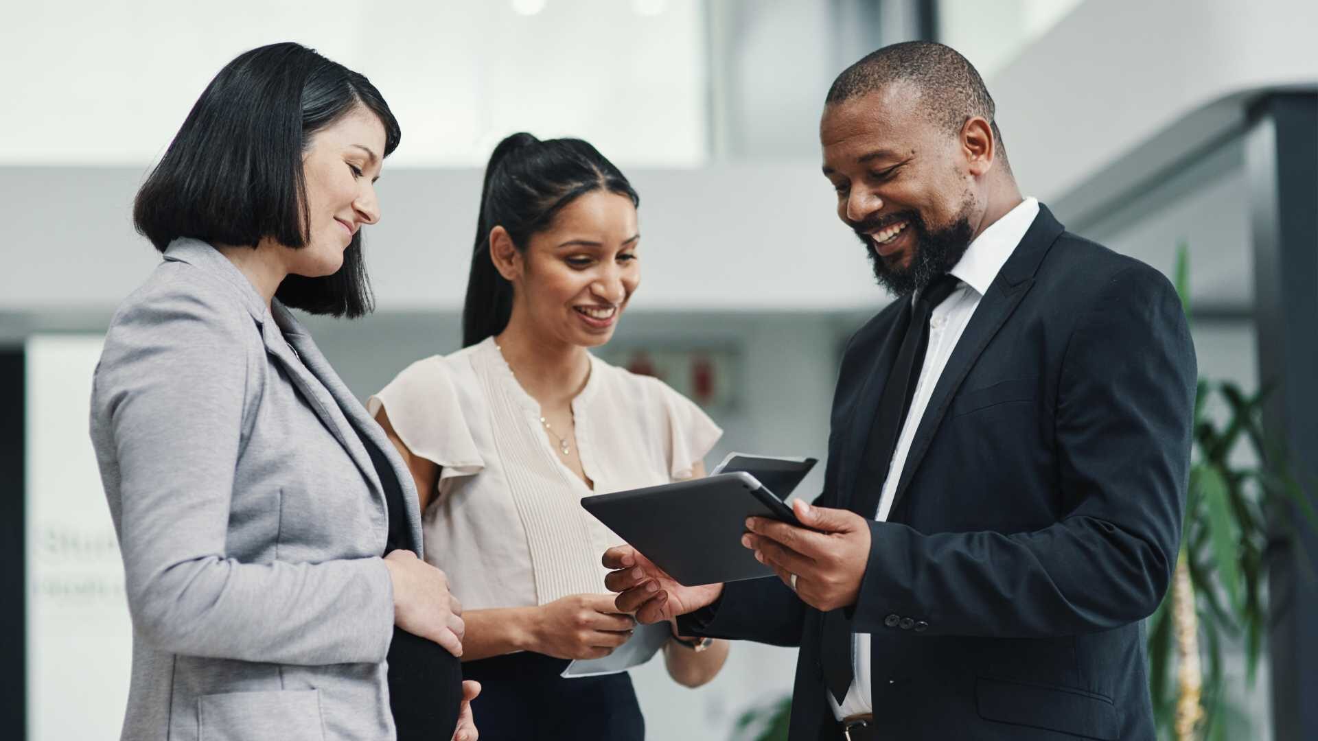 A diverse group of professionals look at a tablet together
