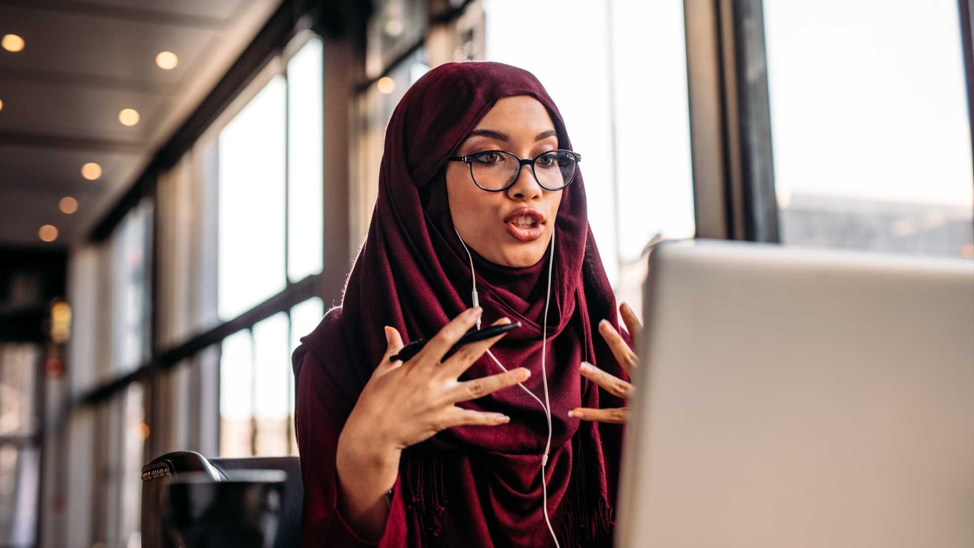 a woman in a virtual meeting talks to her monitor