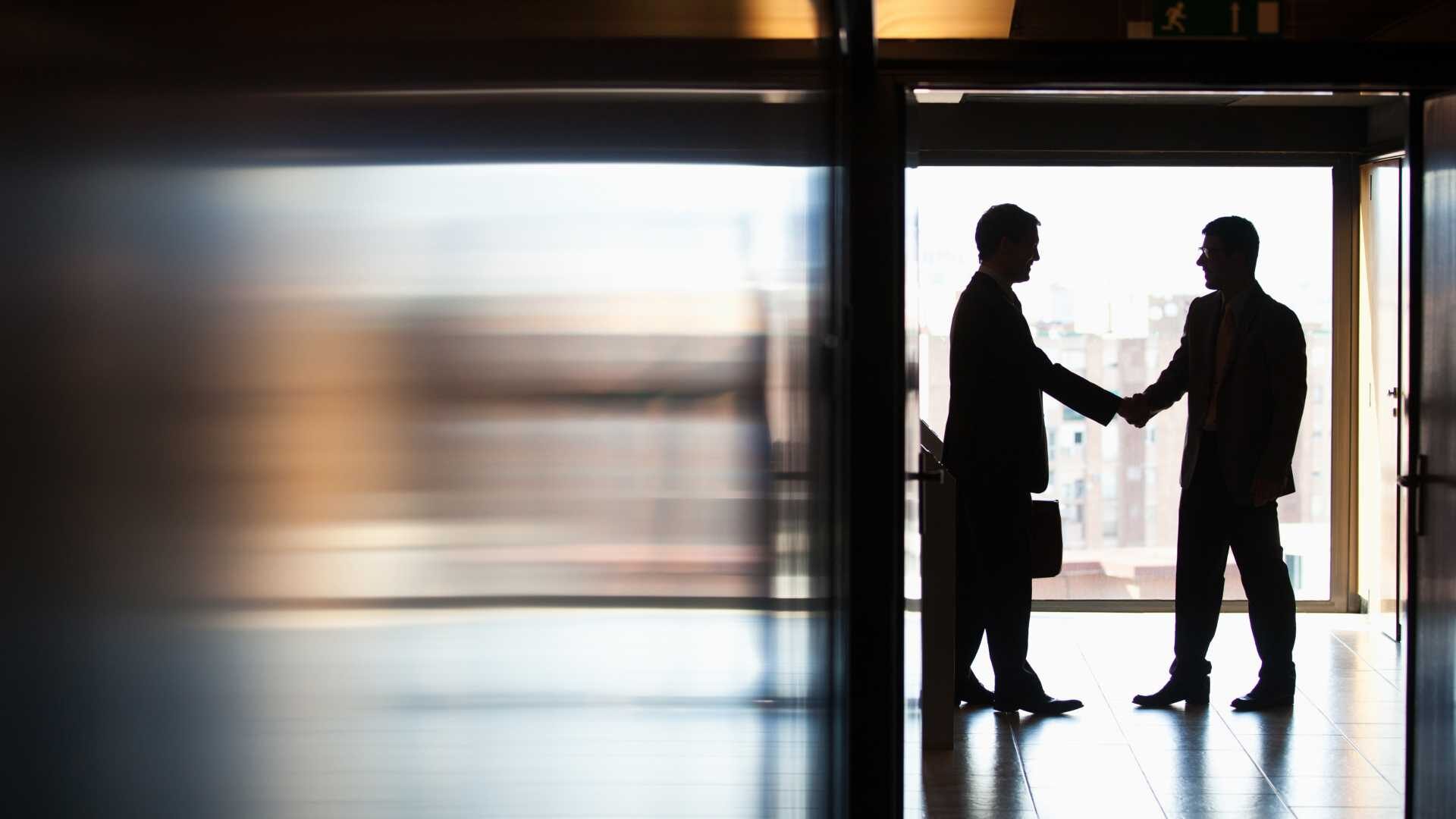 Two men shake hands in a business setting.