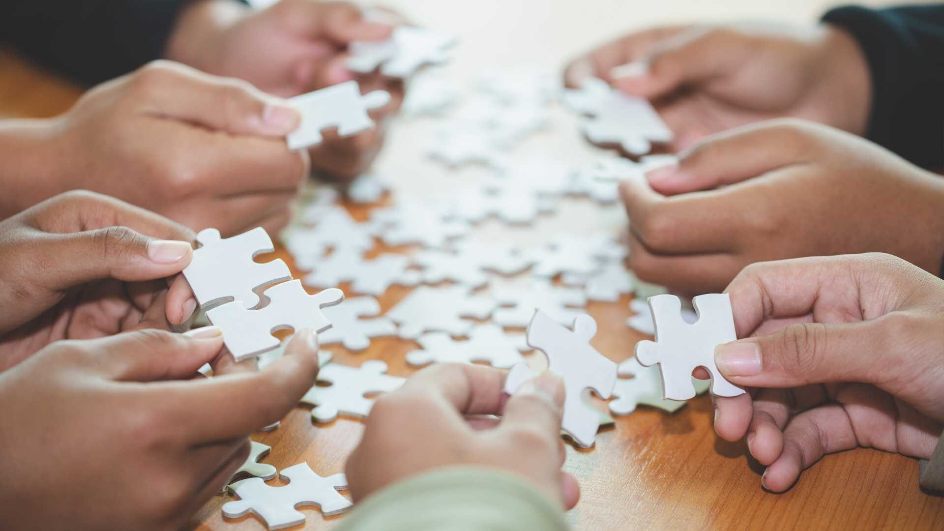 Close up view of hands connecting puzzle pieces