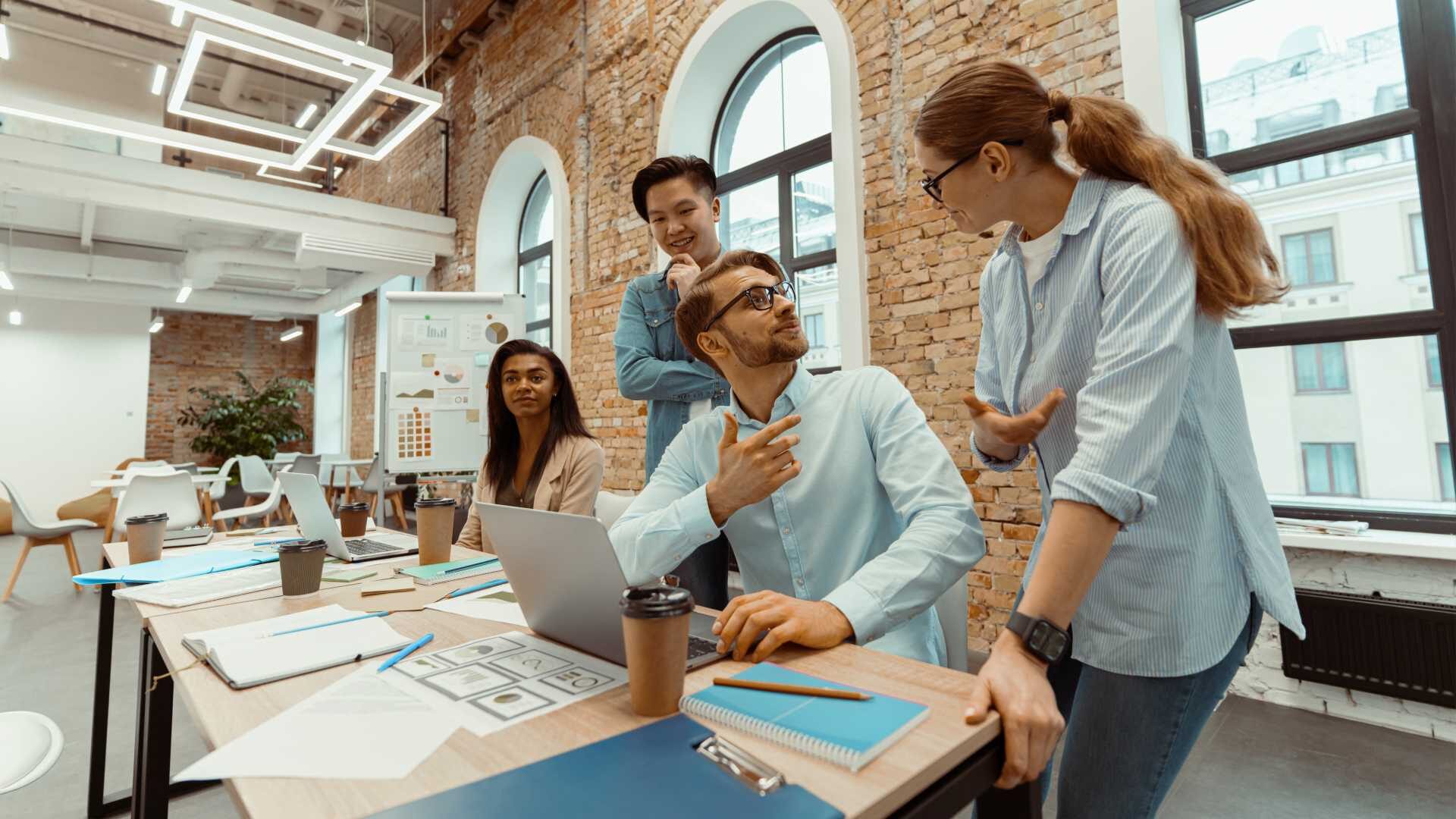 Four people are having a discussion around a computer in an office.