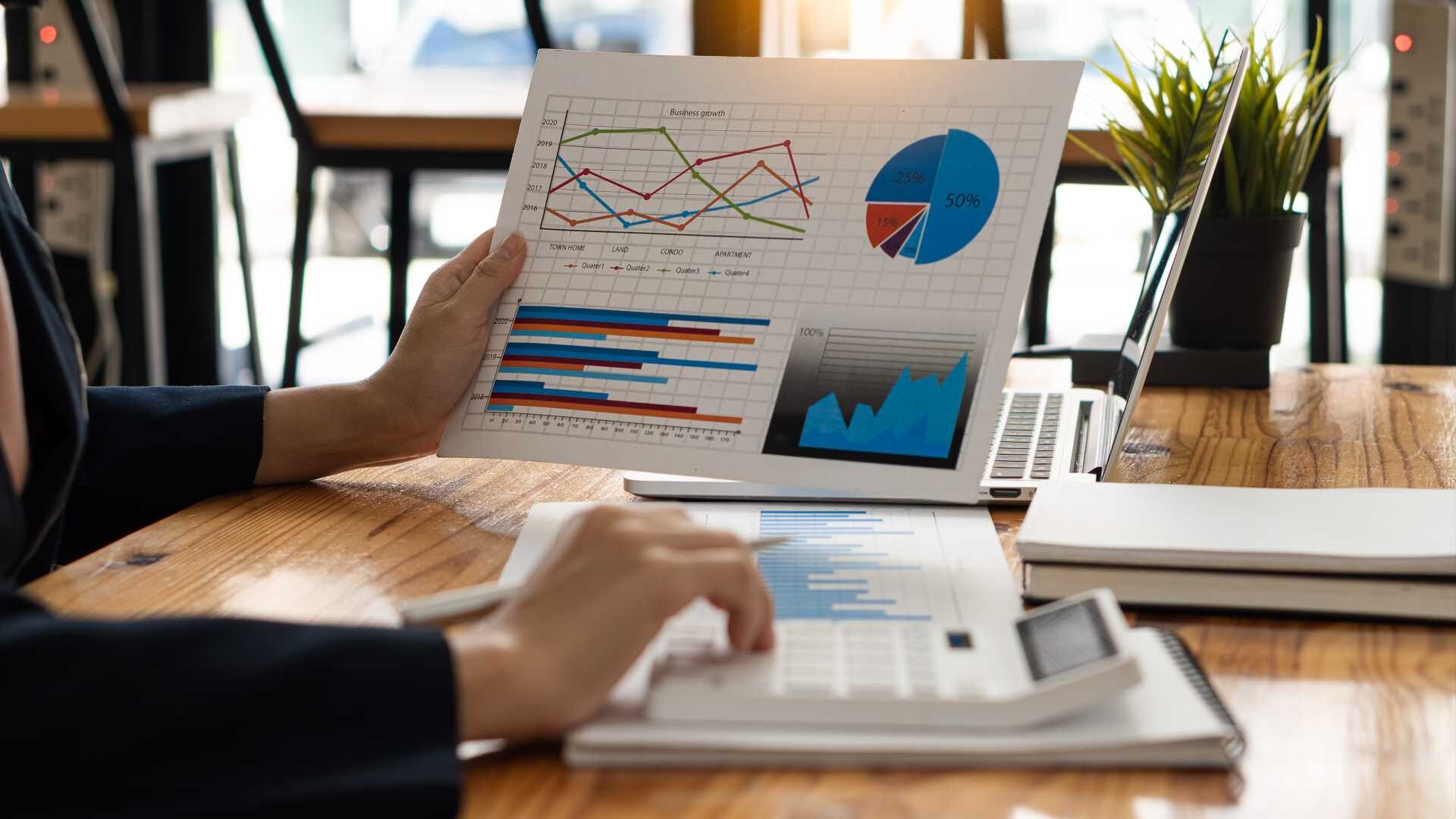 Hand holding up a sheet of data and typing on calculator.