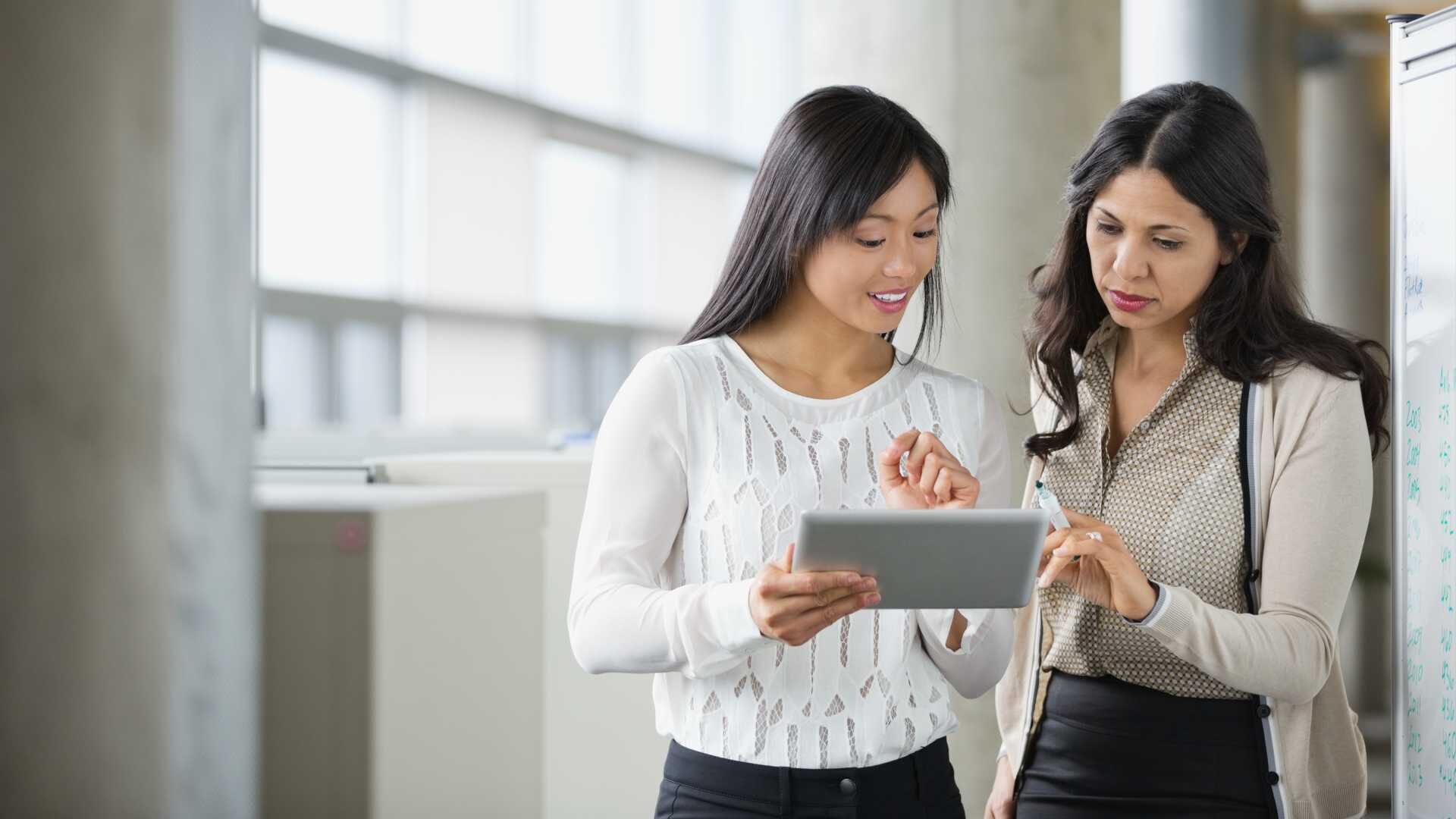 An experienced employee assists a younger employee in a workplace setting