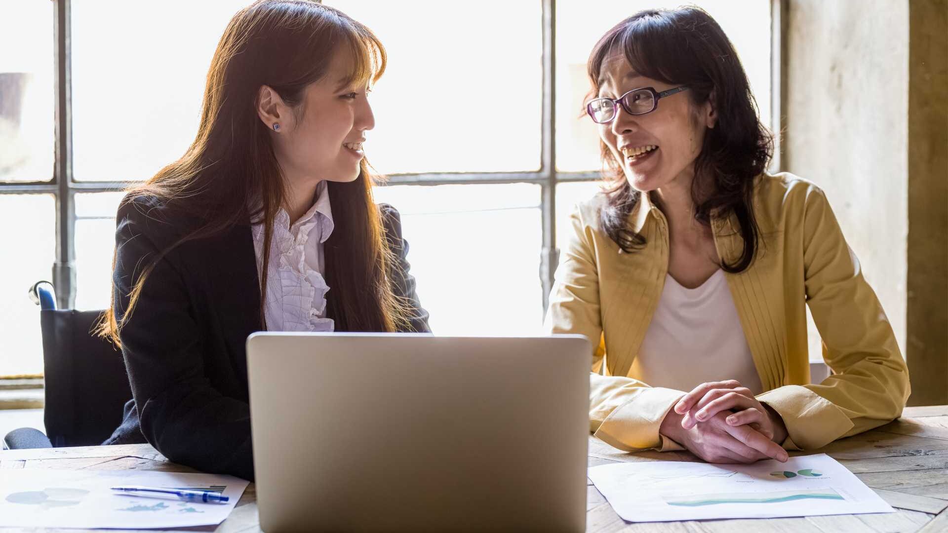 A young employee speaks with a more experienced employee in a business setting