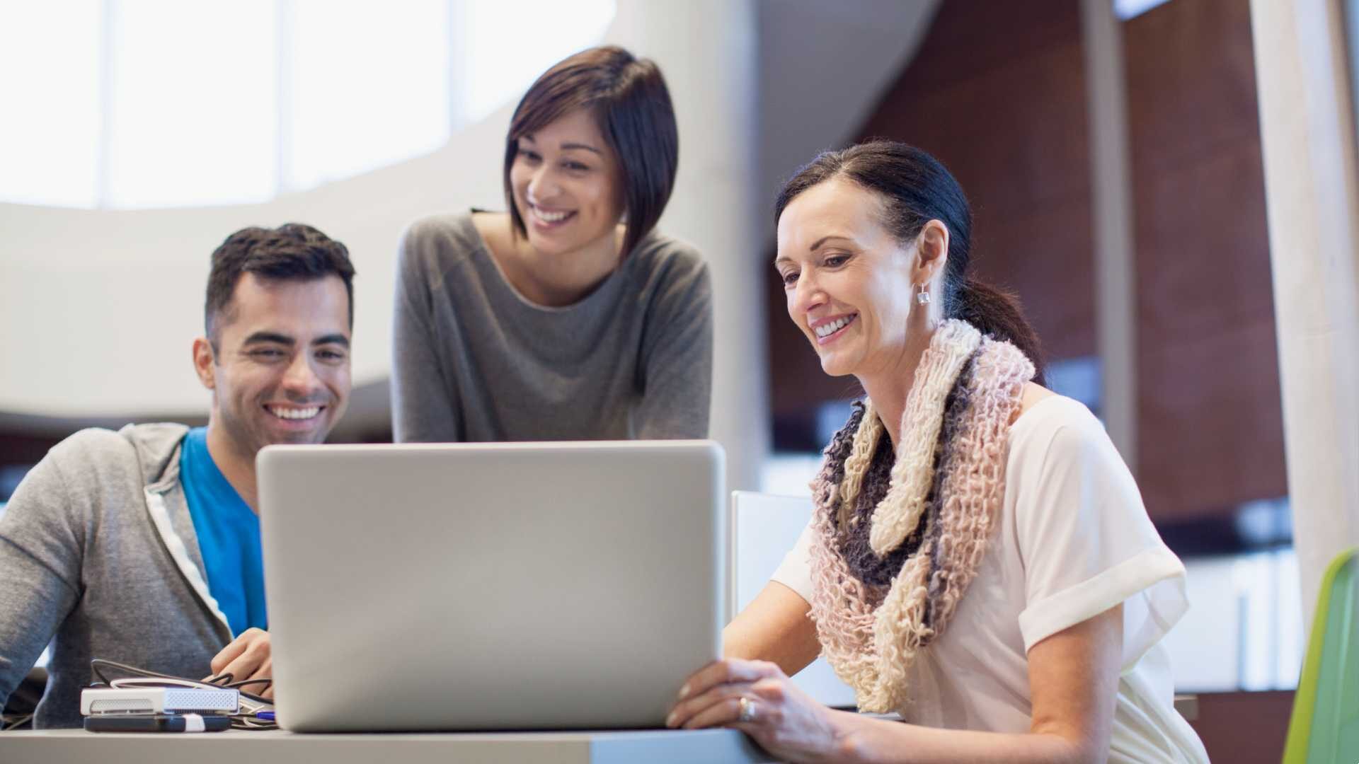 Three colleagues collaborate while working at a computer.
