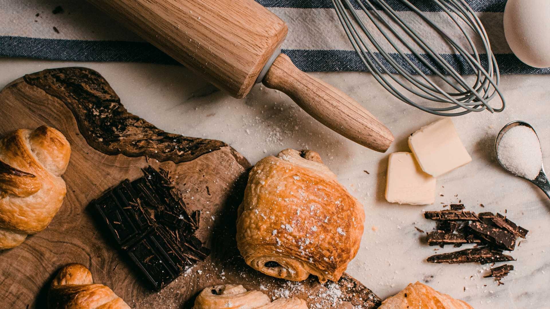 Baked goods lie next to baking tools on a messy tabletop