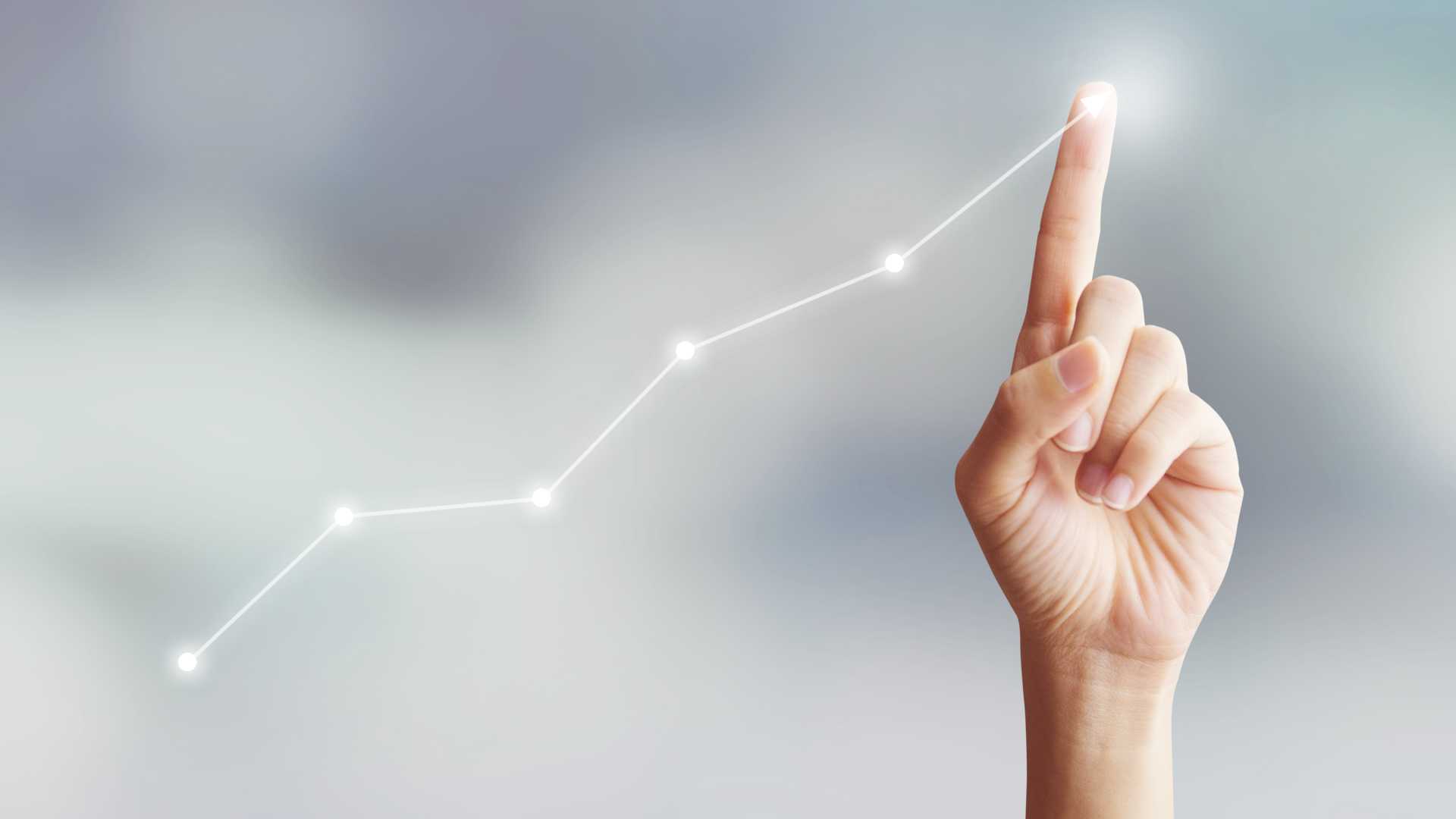 A finger draws an upward graph depicting business growth