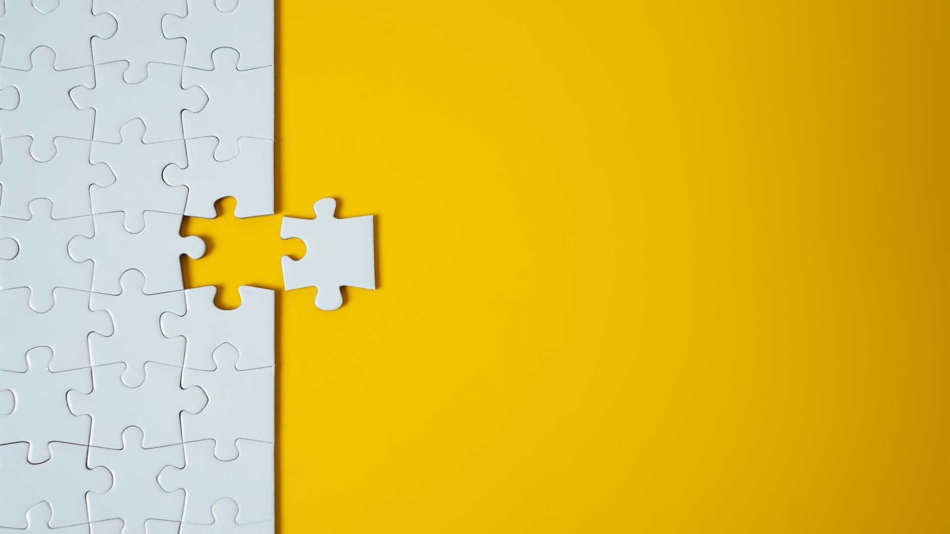 A white puzzle against a yellow background with a missing piece