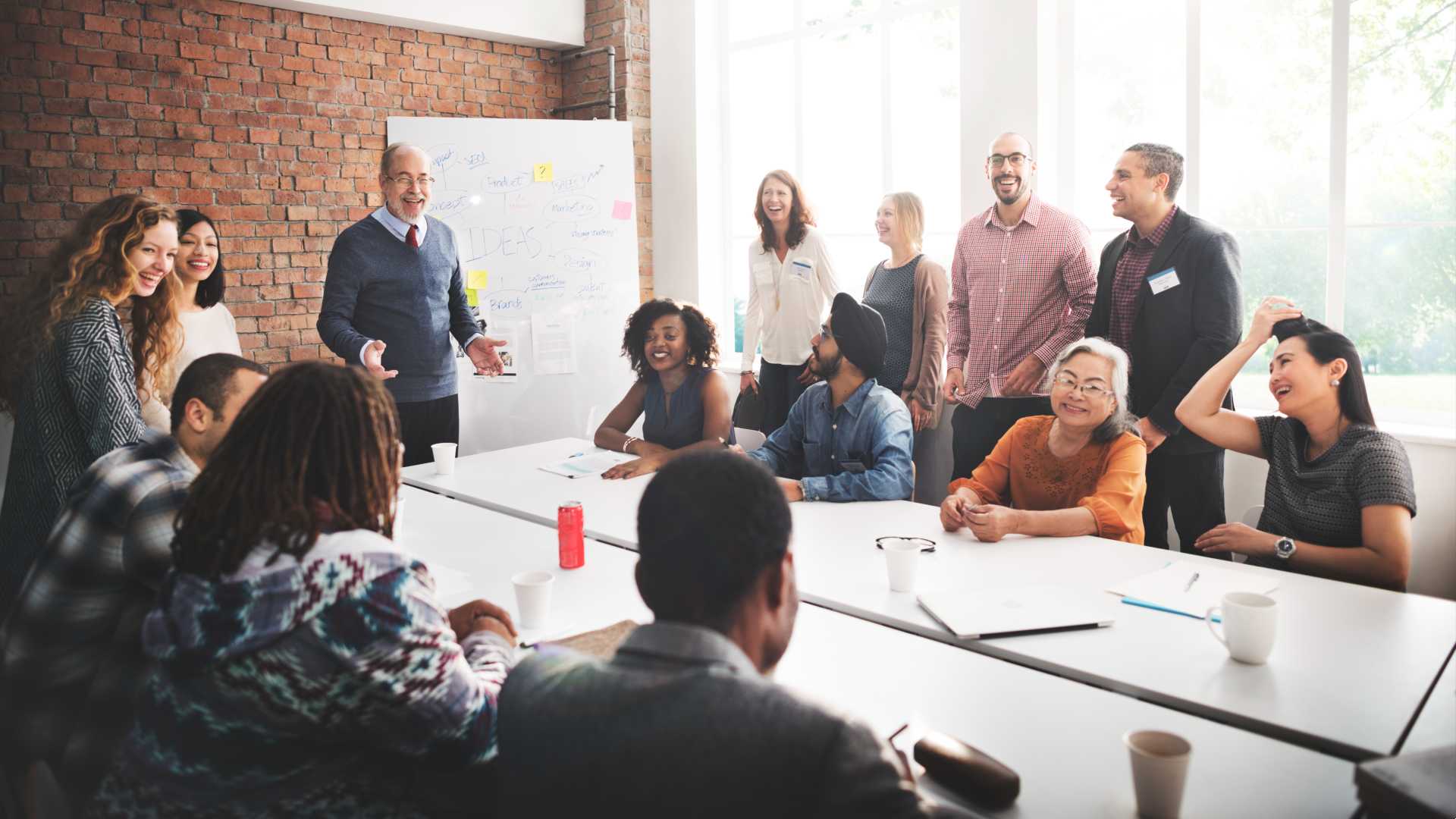 coworkers gathered in a meeting in an office talking and laughing