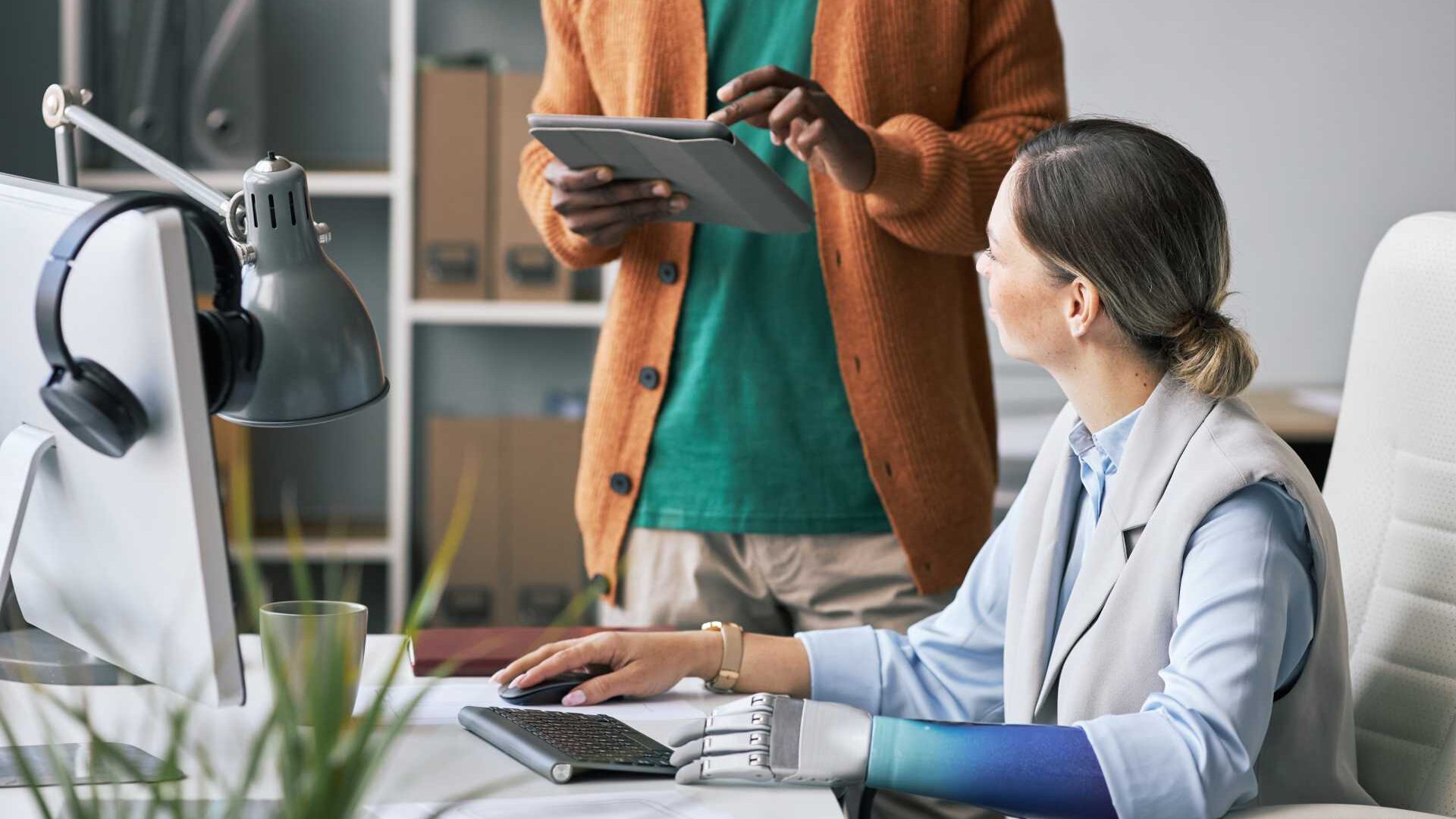 A man going over something with his coworker at her desk.