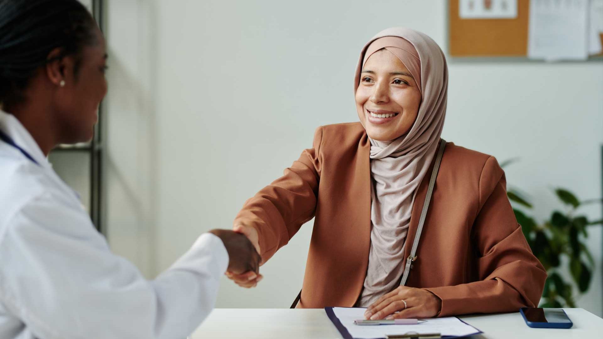 A woman shakes hands with another woman in a professional environment