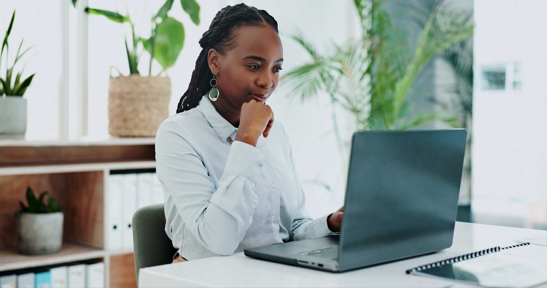 A woman sitting a desk in front of an open laptop